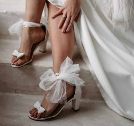 2 Füße mit Brautschuhe mit Schleifen am Knöchel in Ivory